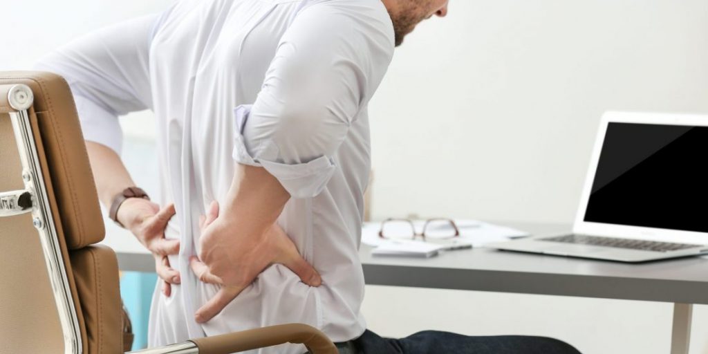 Young Man Suffering From Backache In Office, Closeup