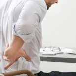 Young Man Suffering From Backache In Office, Closeup