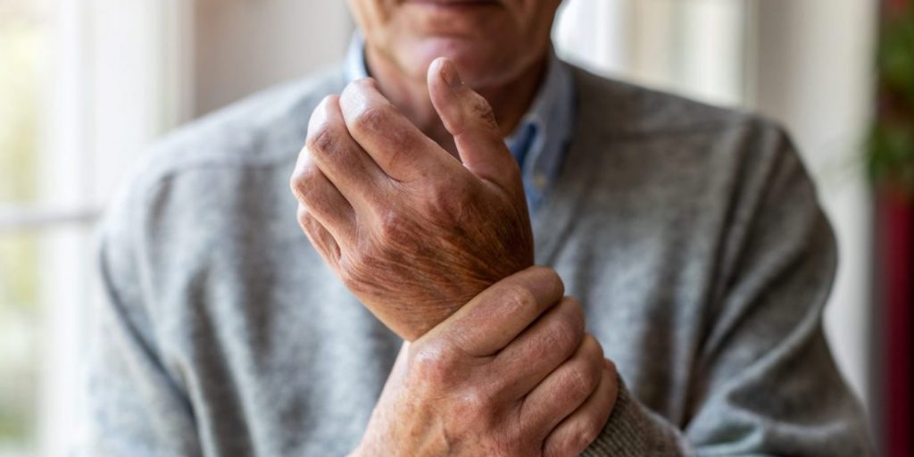 Senior man with arthritis rubbing hands